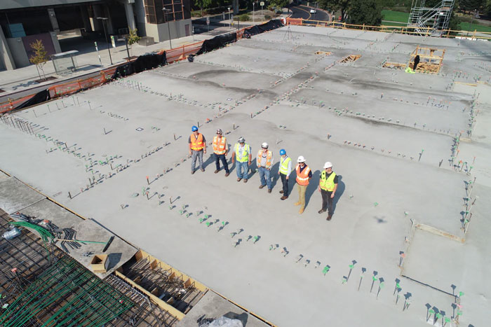 Seven construction workers standing on the roof of a construction project