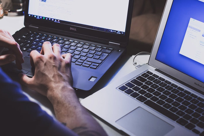 person working on two computers